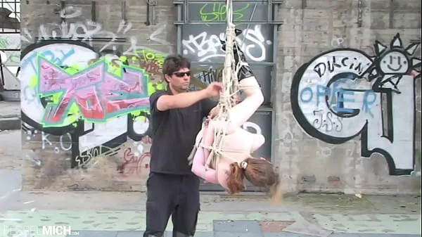 Sexy nackte Frau mit kleinen Brüsten wird von ihrem Rigger gefesselt, das findet in aller Öffentlichkeit statt, aufgehangen an Bondageseilen, ist sie immer mehr ausgeliefert. Die Seile fesseln sie immer weiter ein bis sie kunstvoll eingeschn&uum